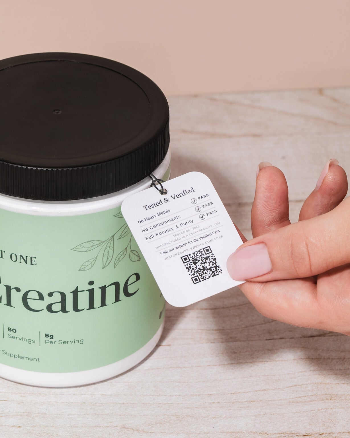 A hand holding the Tested and Verified tag on a jar of Just One Creatine