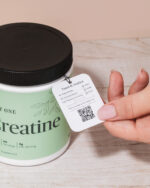 A hand holding the Tested and Verified tag on a jar of Just One Creatine