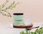 Just One Creatine jar on a wooden tray beside a scoop and a glass of water